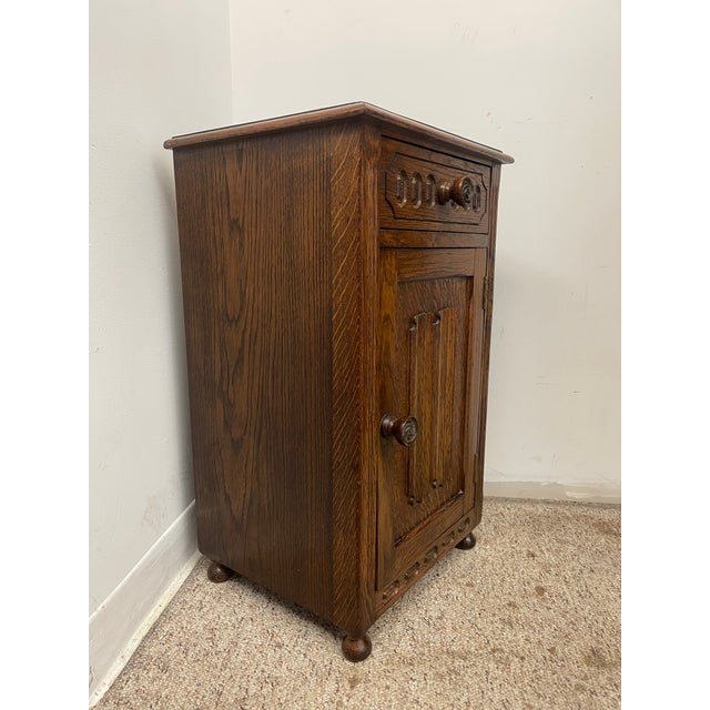 This vintage Welsh style end table cabinet features traditional carved detailing and a compact storage design suited for...