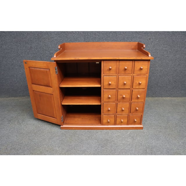 Bench-made solid cherry apothecary cabinet with a distinctive raised tray top featuring shaped gallery sides and curled...
