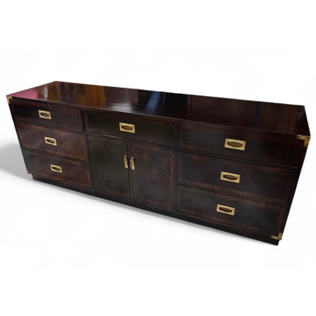 Handsome mid-century modern campaign style credenza or media cabinet featuring a dramatic ebonized case with contrasting...