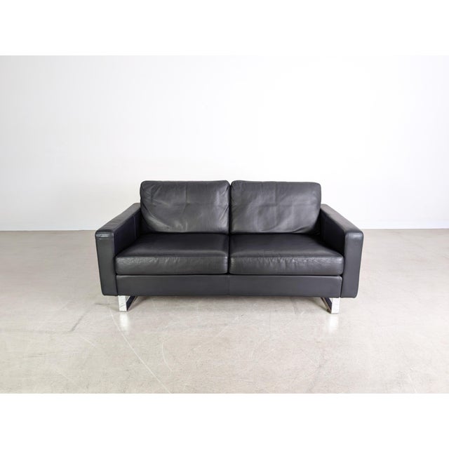 We are offering a beautiful COR Conseta two-seater sofa in black leather for sale. Condition: Good used condition with...