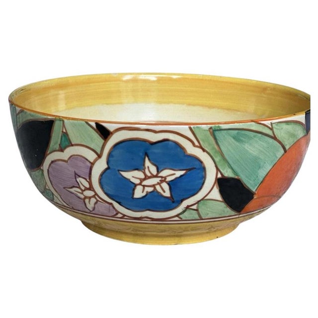 Large orange flowers and broad green leaves cover the outside of this ceramic bowl, with smaller blue and mauve blooms...