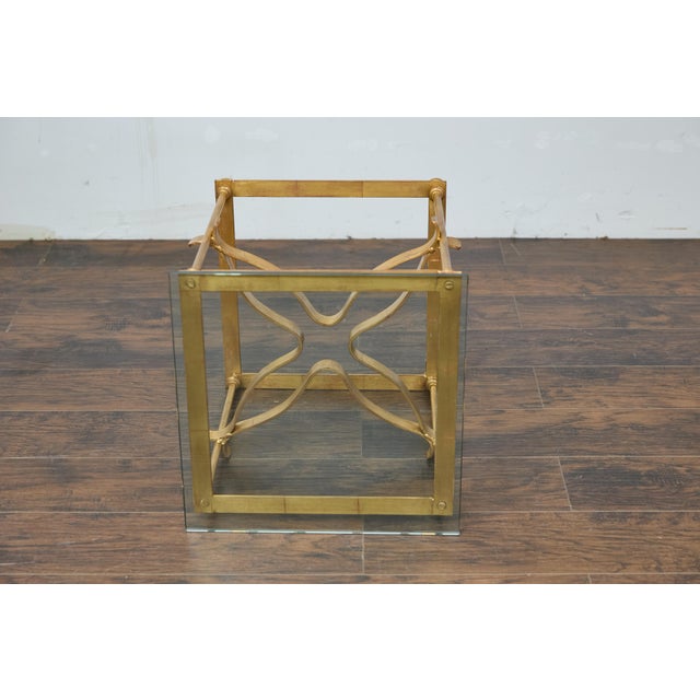 An Italian Midcentury gilt metal cocktail table with glass top and star shaped cross stretcher. This Italian Midcentury...