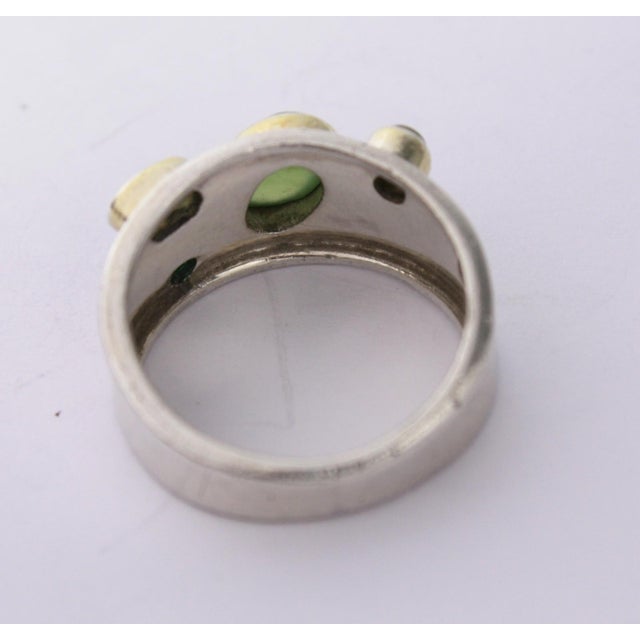 This eye-catching 1990s Sterling Cigar Band Ring with Green Gemstones is a great choice day and night. The simple band...