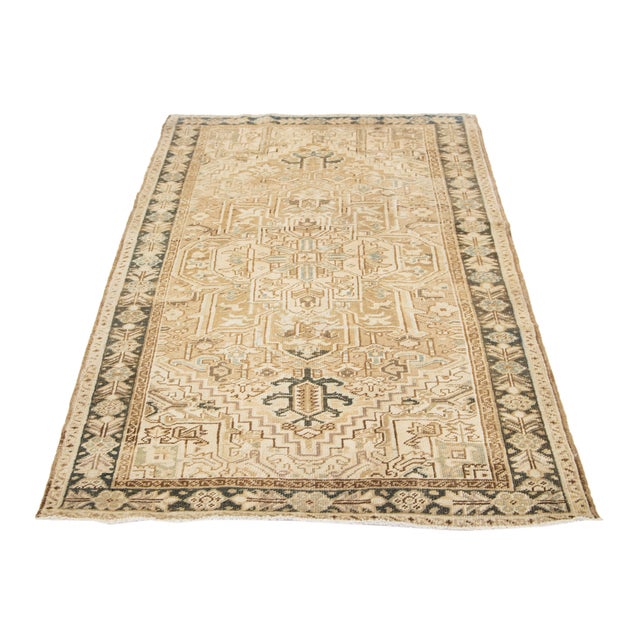 An antique Persian rug with a brown field and blue and rust accents is hand-knotted using wool in an all-over pattern....