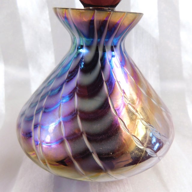 This is a mostly purple but rainbow color iridescent perfume bottle with a matching stopper. The bottle is not marked or...