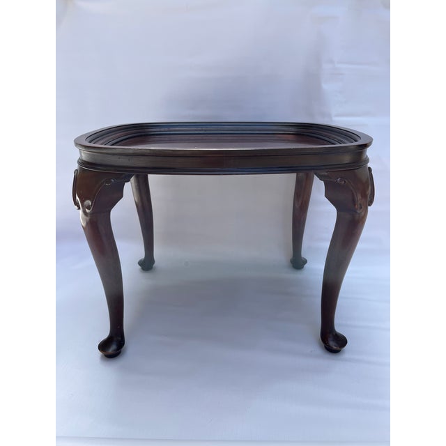 A singe small oval shaped Queen Anne style solid wood coffee table with four carved legs.