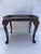 A singe small oval shaped Queen Anne style solid wood coffee table with four carved legs.