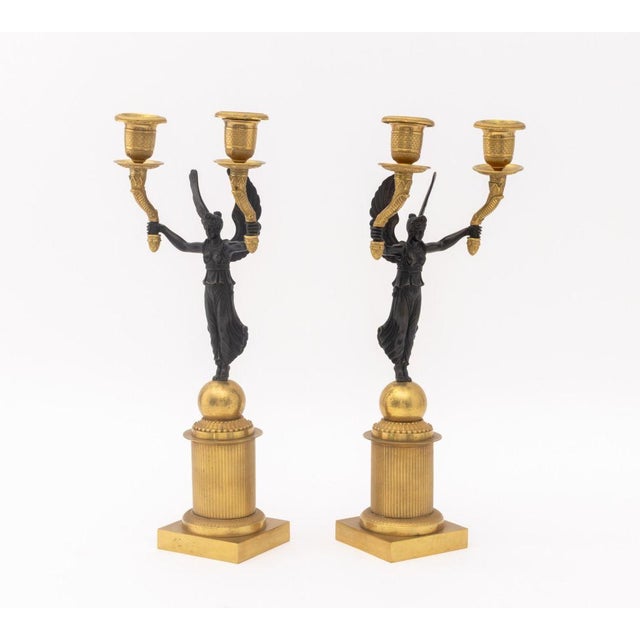 Pair of French Empire Style Patinated and Gilt Metal Candelabra, each depicting Winged Victory upholding two...
