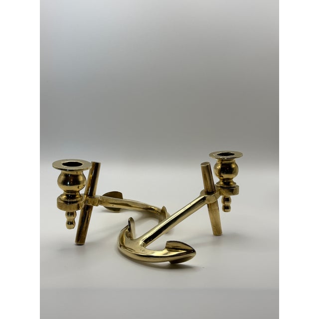 A striking pair of vintage solid brass candlesticks designed as sculptural nautical anchors. Their substantial brass...