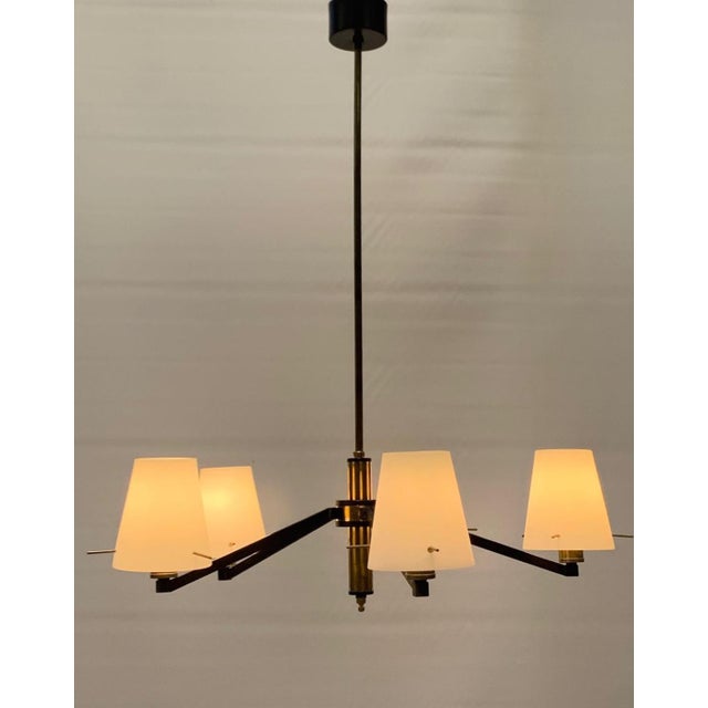 Pendant lamp with a modern and essential design. Metal frame with a black finish and satin brass details. Five linear arms...