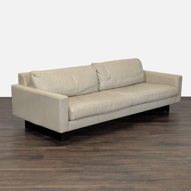 This Room and Board 3-seat sofa features a modern design with clean lines and a neutral light beige leather upholstery. It...
