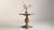 A decorative table featuring carved detailing inspired by Neo-Renaissance forms, paired with a glass top that allows the...