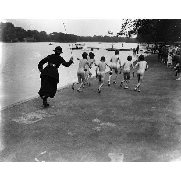 Skinny-Dippers A British policewoman chasing after a group of naked street boys by the Serpentine in Hyde Park, London,...