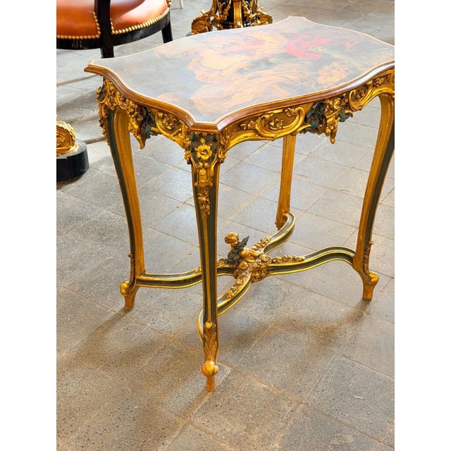 A highly decorative French Rococostyle side table featuring a richly painted top, sculptural gilt detailing, and an...