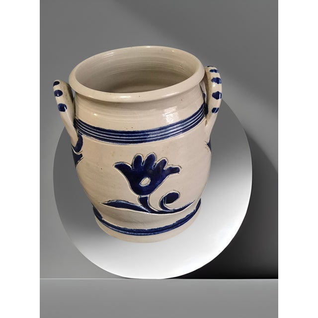 The Williamsburg Pottery Salt Glazed Floral Handled Jar is a beautifully crafted piece of earthenware pottery featuring a...