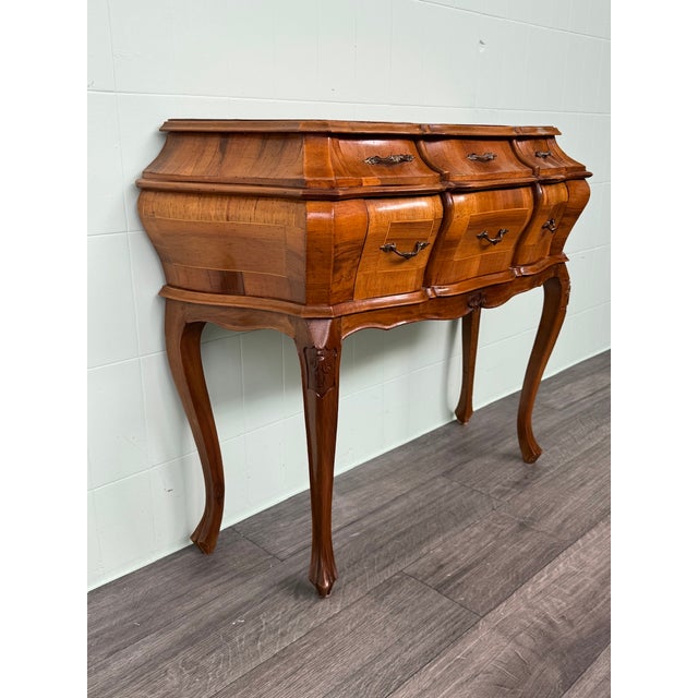 Venetian Baroque console table. Curved walnut cabinet with six small drawers. Saber-shaped legs with carved decorations....