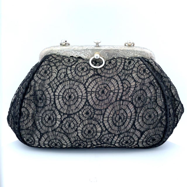 An elegant early-1900s Tiffany & Co. evening purse featuring a finely engraved silver frame with flowing floral motifs and...