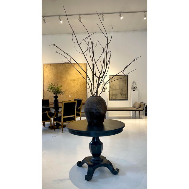 A striking vintage round pedestal table with a sculptural, carved base and a dark warm charcoal grey finish. Early 20th...