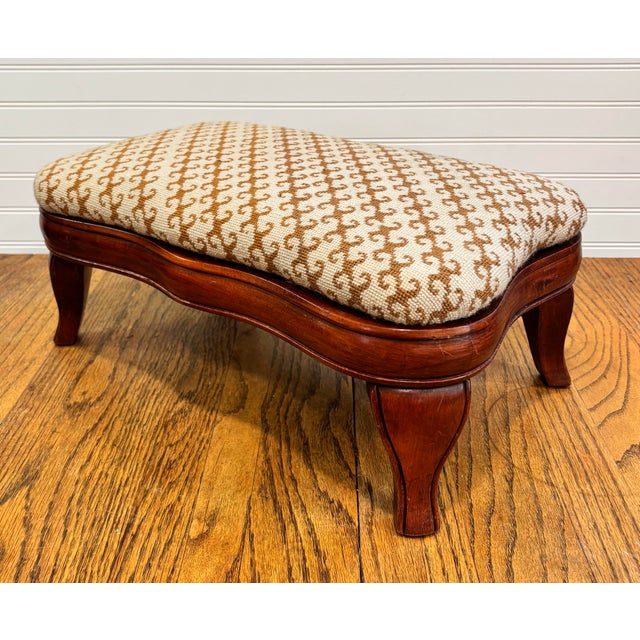 This charming vintage footstool has gently curved wood legs and has been newly upholstered in a mid-century jacquard...