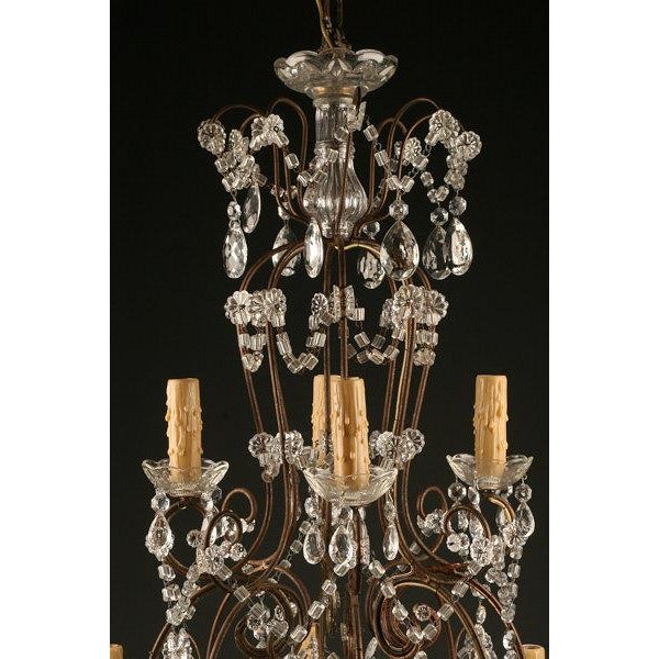 An elegant late 19th-century antique chandelier featuring an iron frame adorned with crystal accents and an impressive...