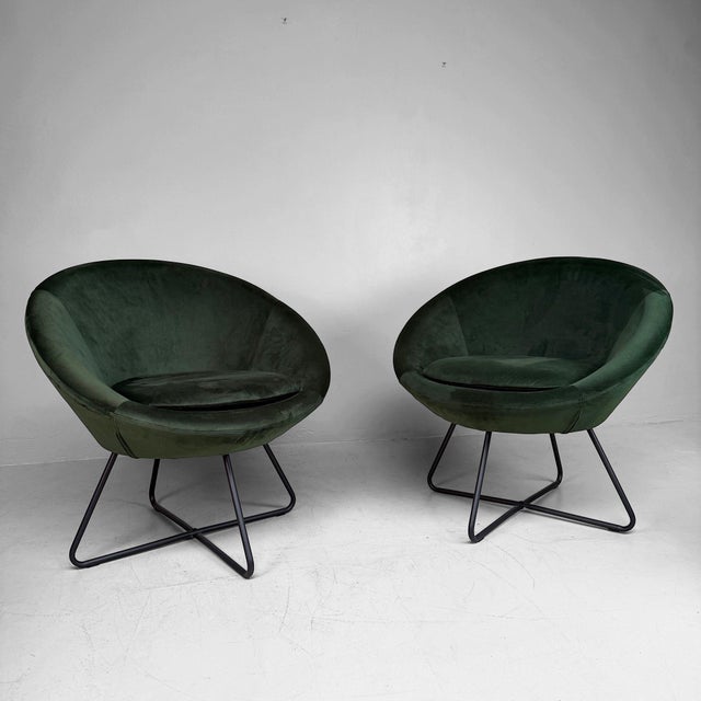Stylish Lucena lounge chair with an elegant retro-inspired design, upholstered in deep green velvet and set on a slim...