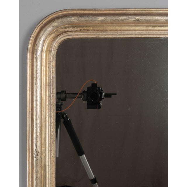 A French Louis Philippe style gilded mirror with curved top corners and incised floral decoration. Pale silvery gilt...