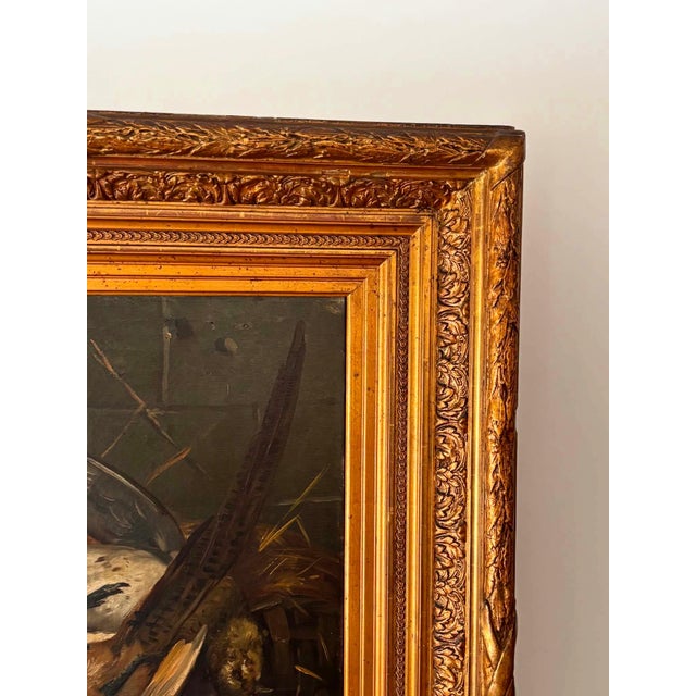 This antique oil painting depicts a traditional hunting still life featuring game birds, painted in rich earthy tones...