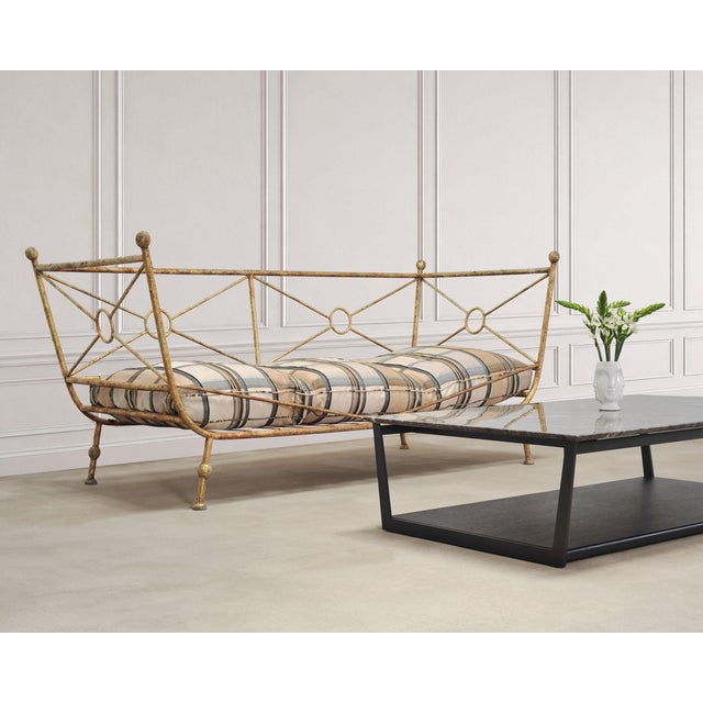 A stunning French mid-20th century modern daybed or sofa crafted in the Neoclassical taste from gilded wrought iron. The...