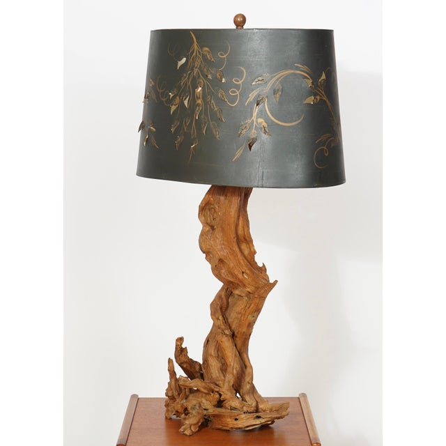 A vintage mid-century organic modern driftwood table lamp featuring a gnarled, weathered wood base and a brass harp.