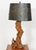A vintage mid-century organic modern driftwood table lamp featuring a gnarled, weathered wood base and a brass harp.