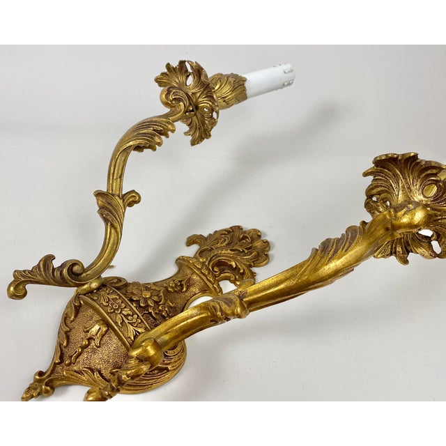 An elegant Pair Of Louis XVI style Wall Lights Circa 1960 in finely chiseled and gilded bronze with two light arms. Fake...