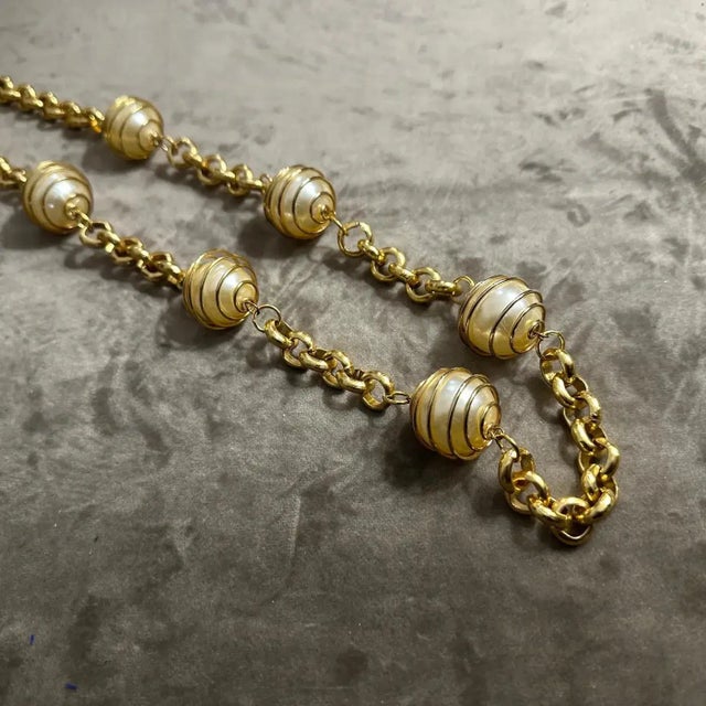 This is a vintage Italian high-quality necklace featuring a striking combination of faux pearls and a brass chain. The...
