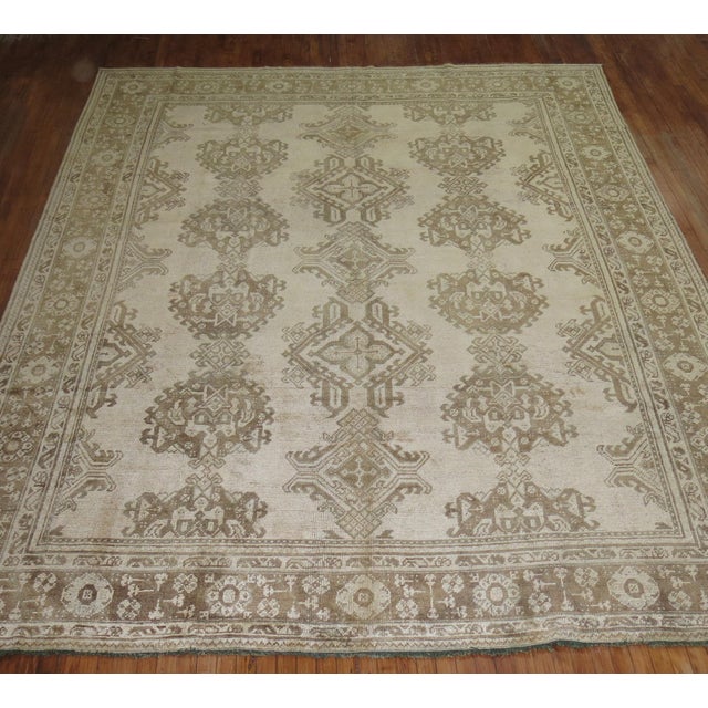 An early 20th century antique Turkish Oushak rug with a beige-colored ground, accents in brown Measures: 9'9'' x 12'2''.