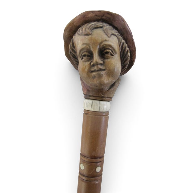 Antique hand carved folk art walking cane with sculpted handle showing the likeness of a young boys head wearing a wide...