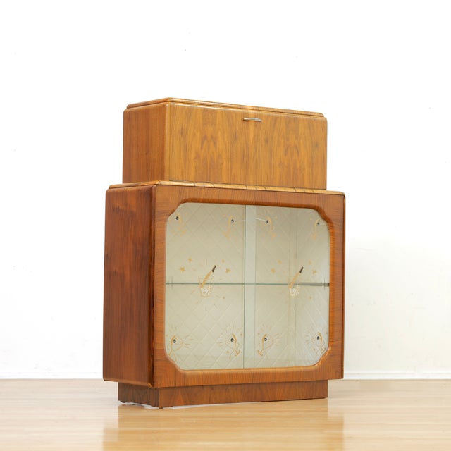 This fabulous mid century liquor cabinet was made in England during the 1950s. Produced in Walnut, this fantastic bar is a...