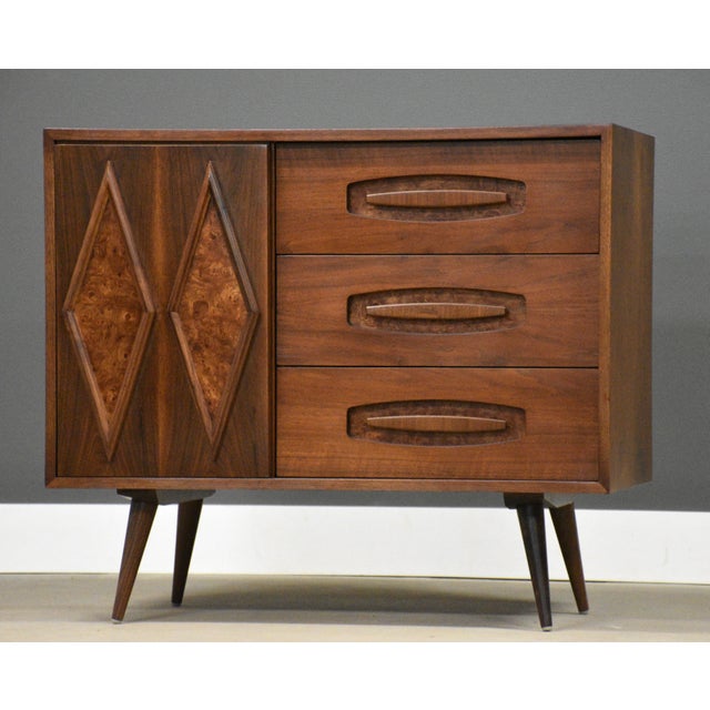 A mid century modern walnut six drawer dresser chest with a sliding door, burl details and long canted legs....