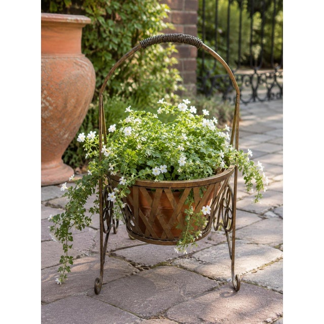 A charming vintage decorative metal garden planter basket distinguished by its sculptural silhouette, woven lattice...