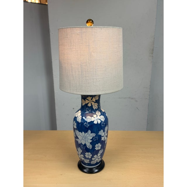 Design Plus Gallery presents a Blue with White Flower Table Lamp. The body of the lamp is vase like and porcelain with a...