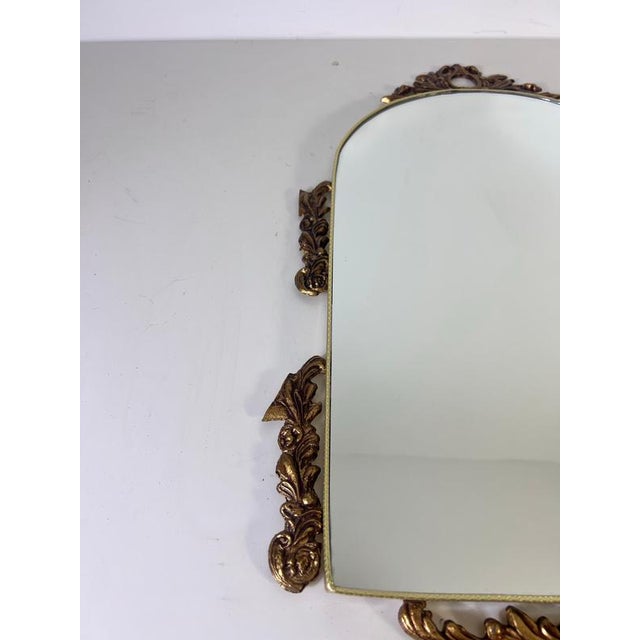 Italian ornate brass framed wall mirror, Italy, 1960s. This decorative vintage mirror features a softly arched mirror...