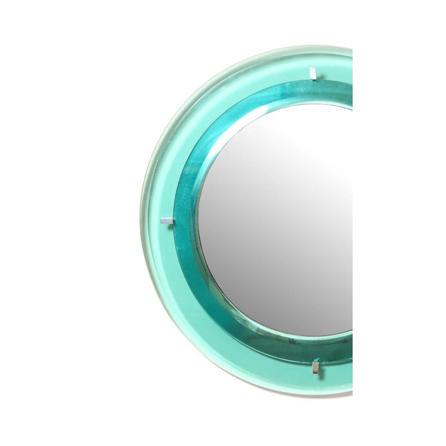 A 1960s Italian wall mirror attributed to Fontana Arte. The round central mirror is held within a pale aqua glass...