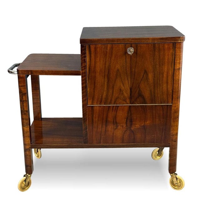 An elegant Art Deco bar cart on casters, combining practicality with the refined aesthetics of the interwar period. The...