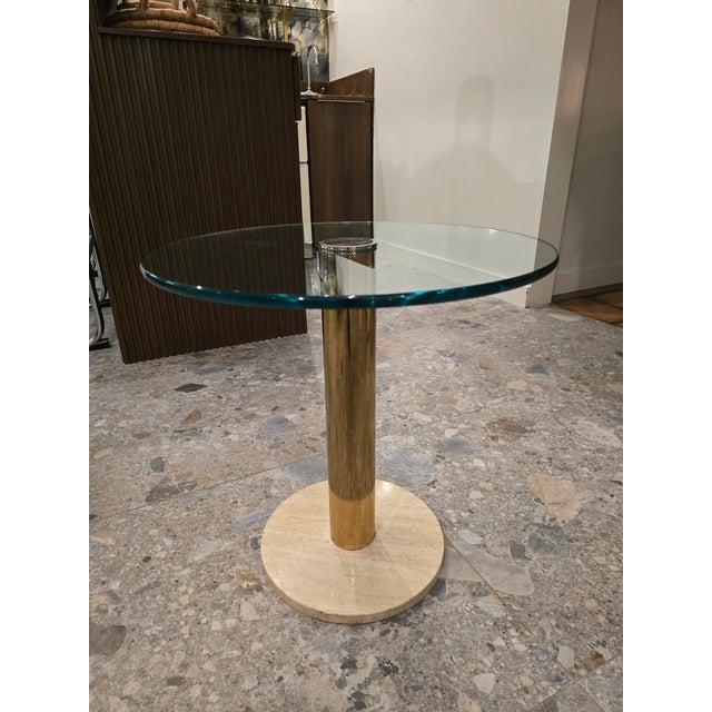 ▪️Leon Rosen for Pace Round Glass, Brass and Travertine Side Table Attributed ▪️Brass cylinder rising appearing to...