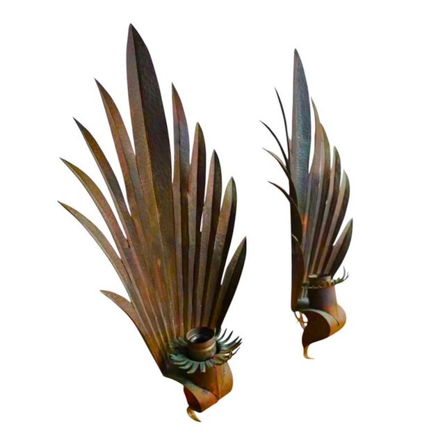 A striking pair of monumental wall sconces in hand-hammered copper, each conceived as a sweeping palm frond rising in...