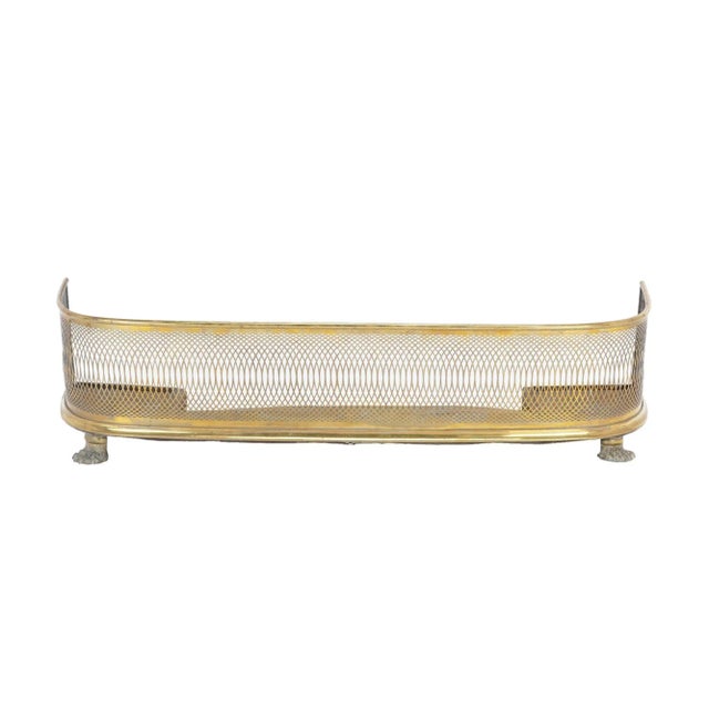 Brass and steel fire fender with a delicately pierced pattern of rhythmically spaced arcs between brass moldings. The...
