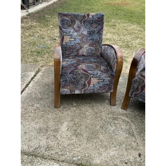 Elegant pair of 1930s Art Deco lounge chairs featuring beautifully curved wooden armrests and a classic silhouette. These...