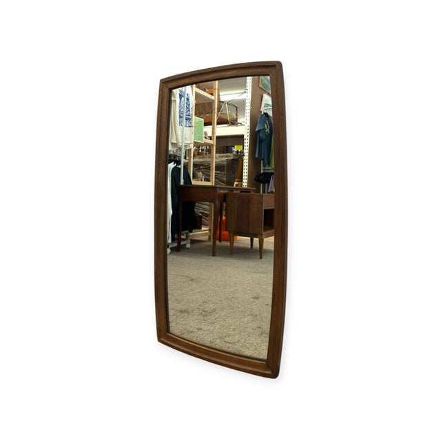 This vintage mid-century modern wall mirror features a distinctive gently bowed, barrel-curved solid wood frame with...