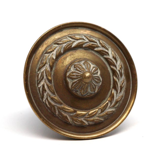 Concentric floral wreath design knob made of brass in an antique finish. The manufacturer and exact date of creation is...