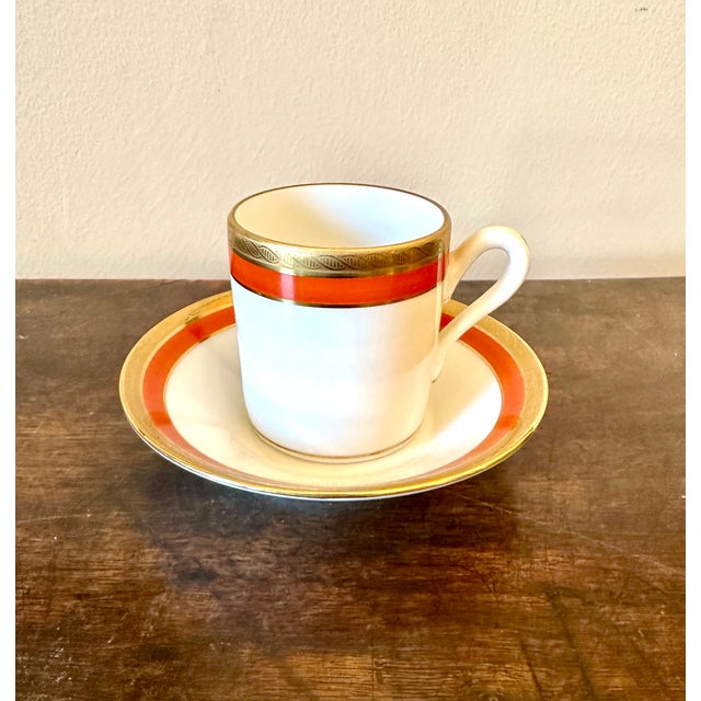 A pair of Richard Ginori Impero demitasse espresso cups and saucers. One in red and gold, one in black and gold.