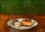 This oil painting presents a delectable arrangement of desserts on a delicate plate, featuring a vibrant orange treat...