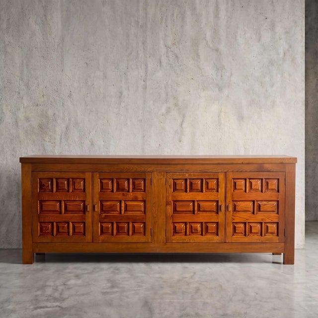 Bold geometric massing meets warm, tactile woodgrain in this monumental four-door enfilade. Deeply carved block motifs...